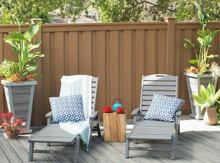 pbs-new-home-trex-fencing-and-transcend-decking (1) A Trex Saddle Fence behind a Trex Transcend Island Mist deck with deck chais and plants.