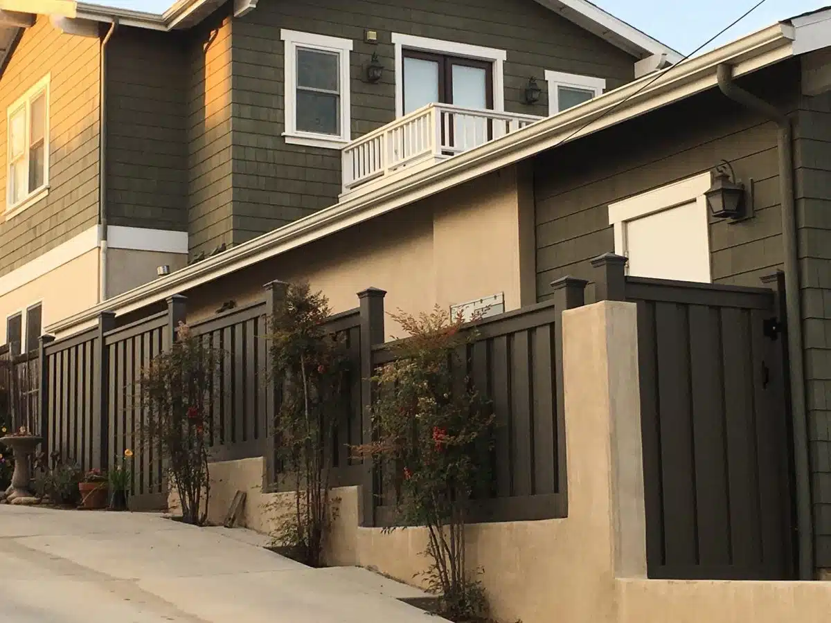 trex-fencing-stair-stepping-on-wall Trex Fencing panels mounted on top of a stucco wall next to a driveway. The fence stair steps up the wall.